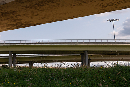 Snelwegbrug tegen blauwe lucht met gras op de voorgrond